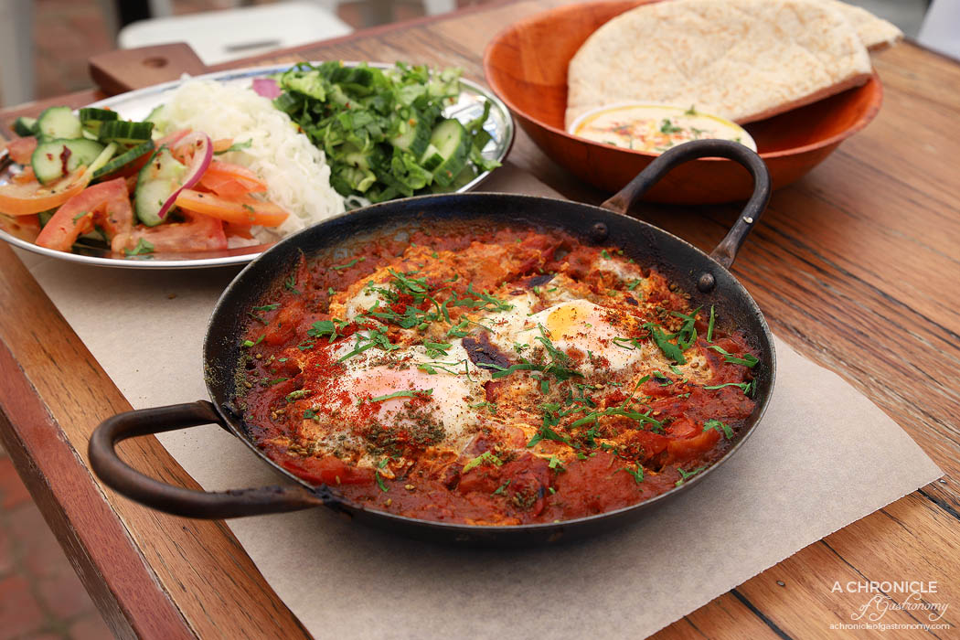 Tahina Fitzroy - Red Shakshuka - Two free range eggs with traditional tomato base with mixed herbs. Served with Israeli salad, spicy green salad, pickled cabbage, hummus, tahini and pita bread ($15.50)