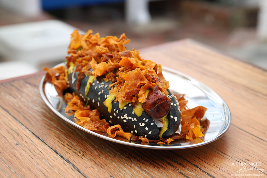 Tahina Fitzroy - Vegan Carrot Hotdog - Black smoked bun with pickled cabbage, spiced cured carrot, tahini amba mustard and sweet tomato sauce sprinkled with sweet potato chips ($12,50)